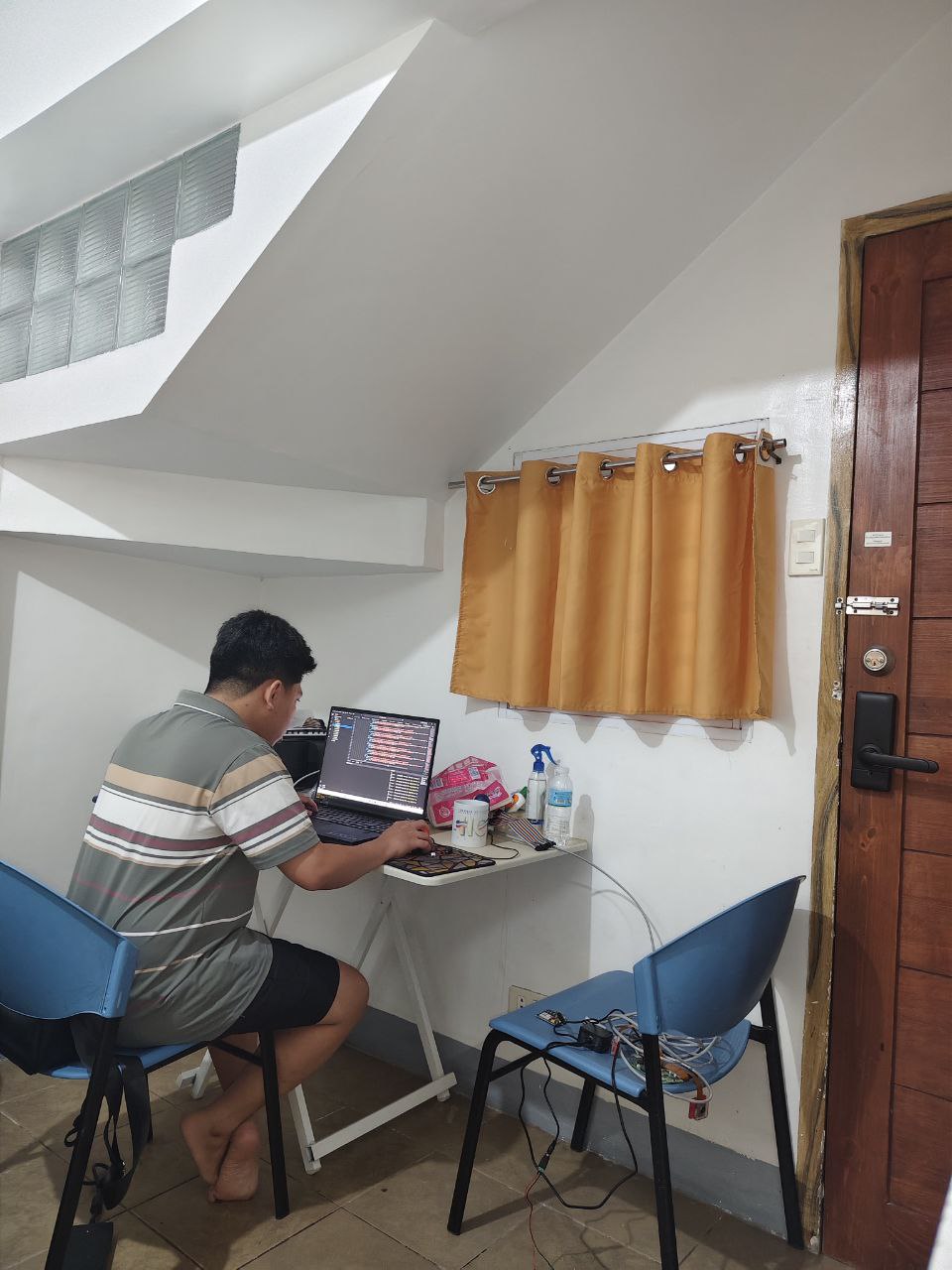 A developer focused on his laptop in a simple workspace.